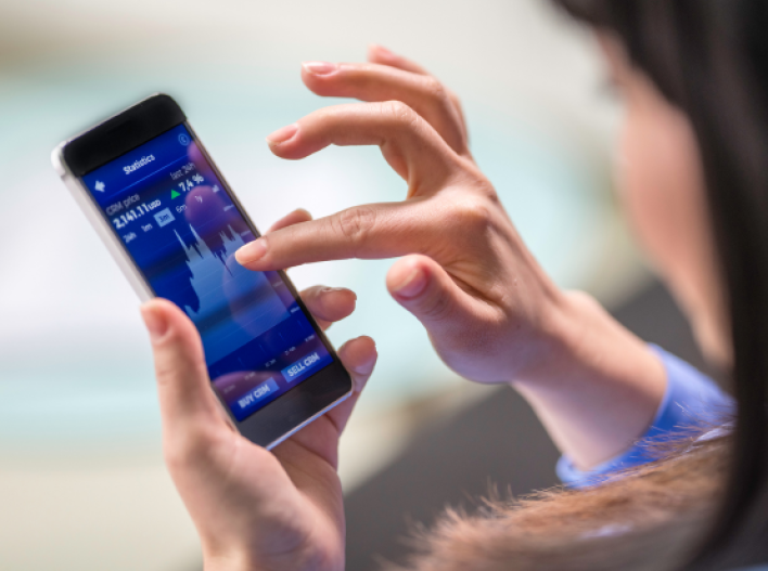 Woman with mobile phone and stock market