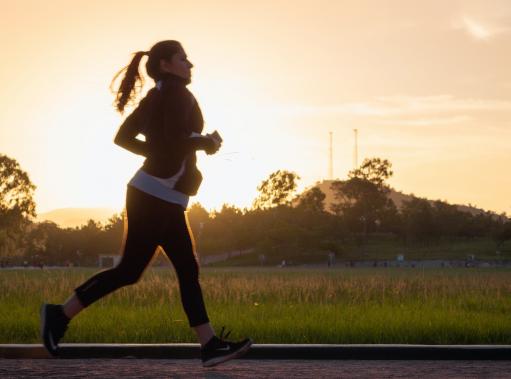 Running woman in fog at sunrise.